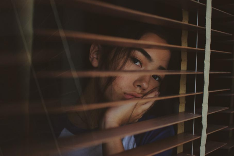 A woman touching his face as she sits sadly 