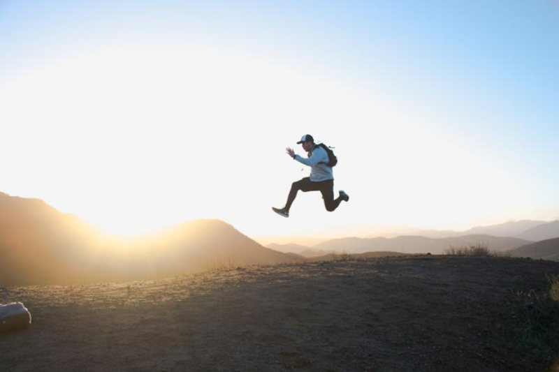 A man jumping in excitement in a hilly area